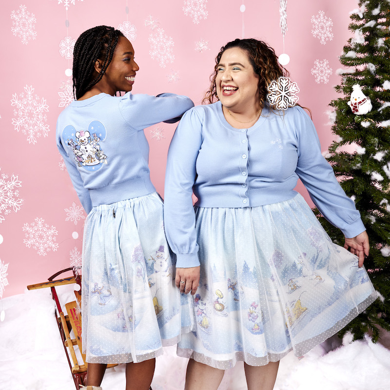 Two women wearing the Stitch Shoppe Mickey and Friends Winter Snow Cardigan and Tulle Overlay Skirt, showing off the front and back of the outfit against a wintery background